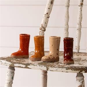 Four pairs of vintage-style rubber boots on a rustic wooden table with white birch trees in the background.