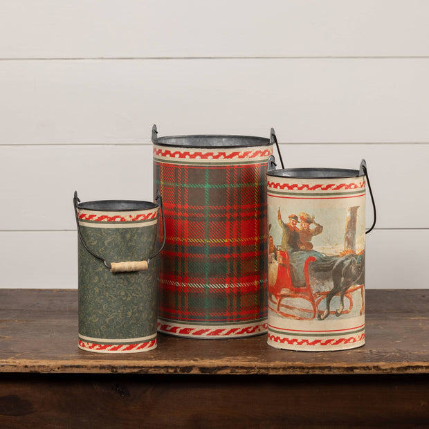 Three decorative metal buckets with plaid and vintage designs on a wooden surface.