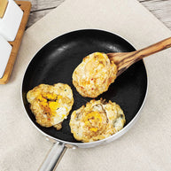 Fried food items being served in a frying pan with a wooden spoon.