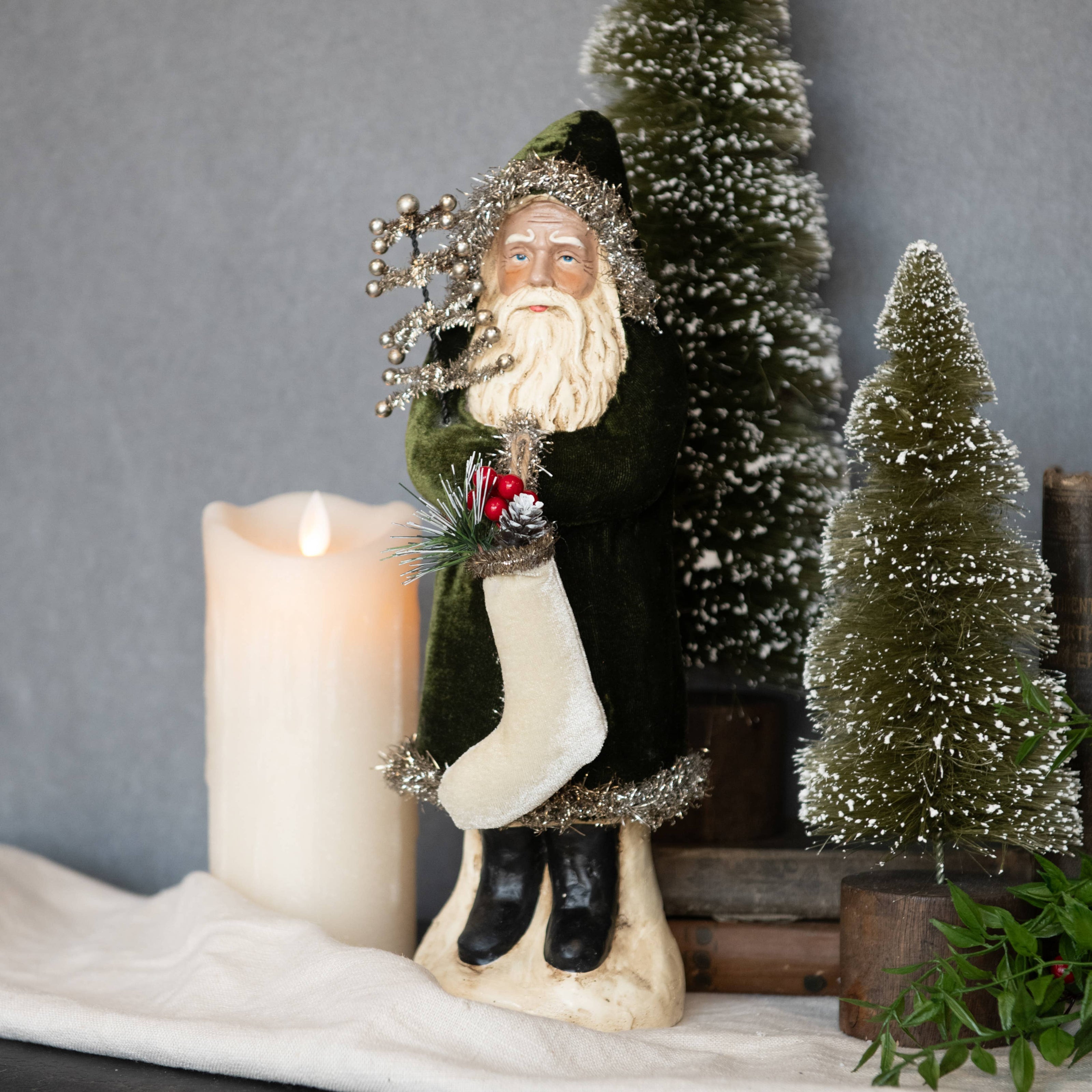 Decorative figure of a winter scene with a candle and small trees on a gray background