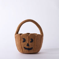 Brown pumpkin-shaped basket with a black face on a white background