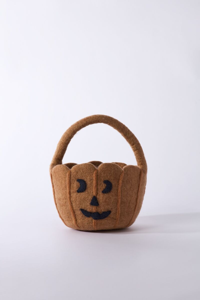 Brown pumpkin-shaped basket with a black face on a white background