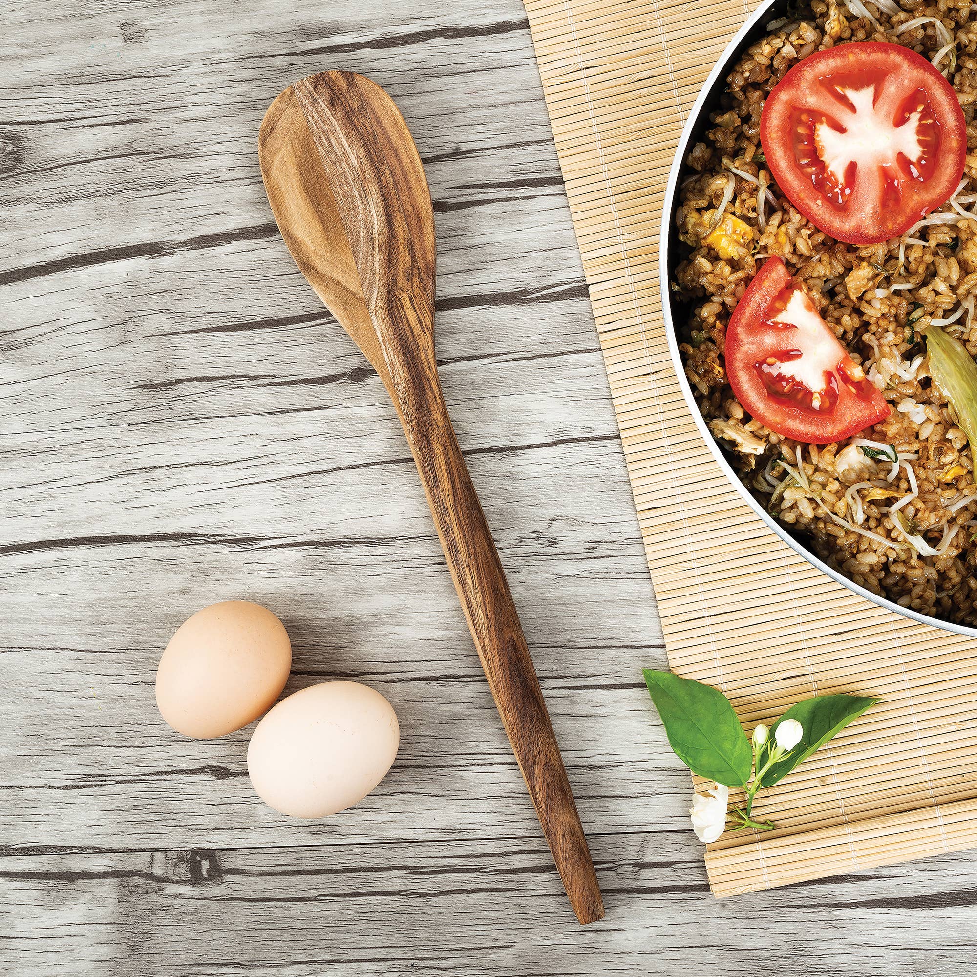 Wooden spoon next to eggs and a dish of food on a wooden surface