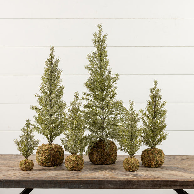 Set of six small artificial trees on a wooden table with a white wooden panel background