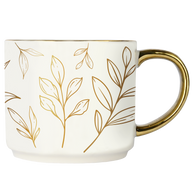 White mug with gold leaf patterns and a gold handle on a white background