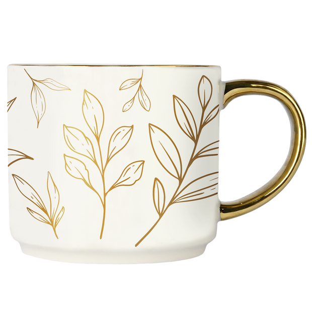 White mug with gold leaf patterns and a gold handle on a white background