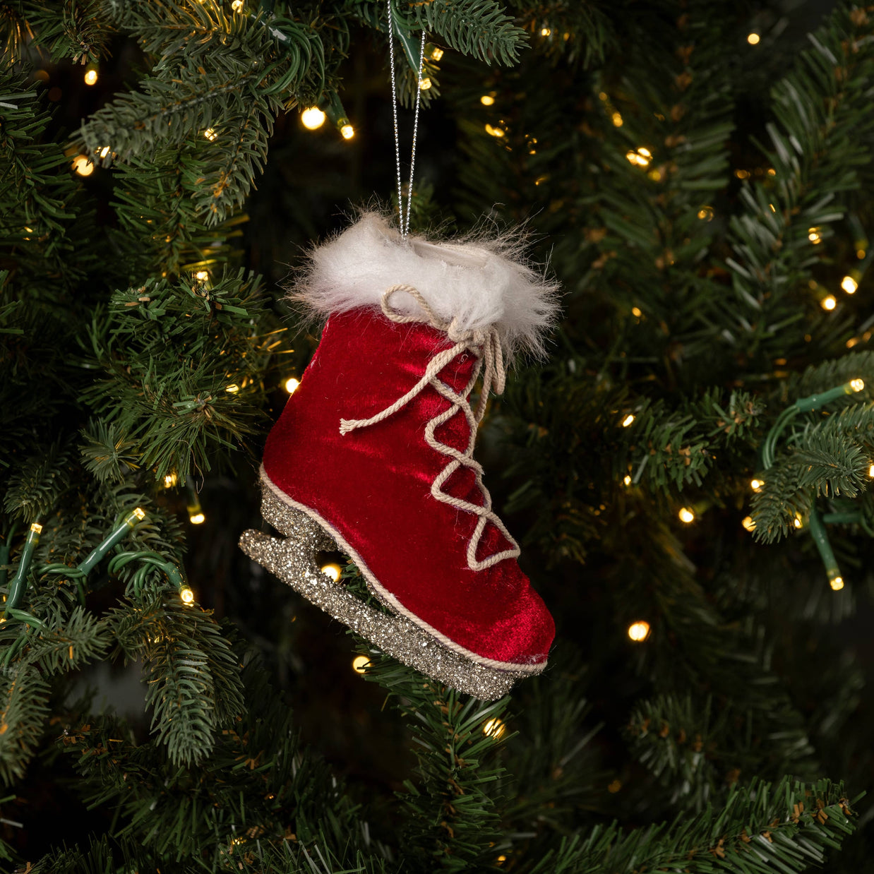 Red velvet ice skate ornament on a Christmas tree with lights