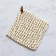 Beige woven potholder with leather strap on a light marble background