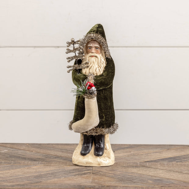 Decorative figure of a bearded man in a green coat holding a tree on a wooden surface with a white background