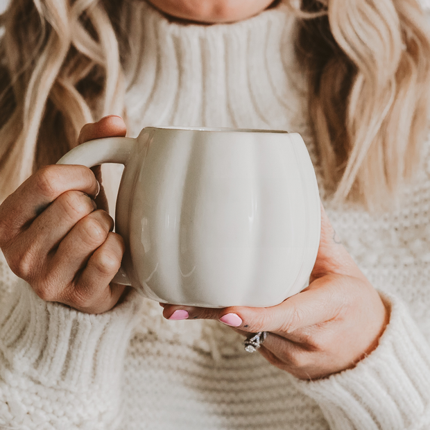 Person holding a white mug with a soft focus background