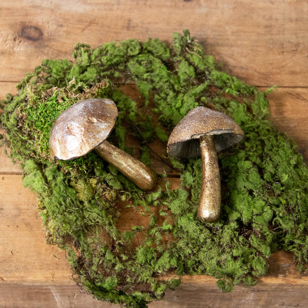 Decorative wreath with moss and two metallic mushrooms on a wooden surface