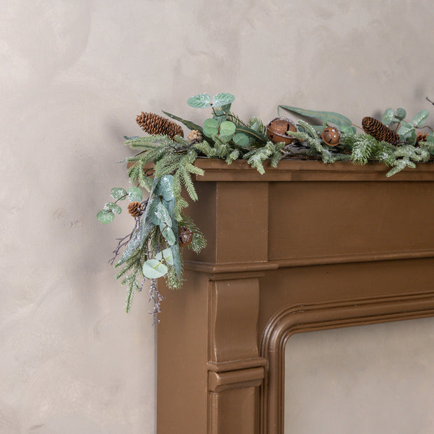 Decorative greenery on a brown fireplace mantle against a beige wall.