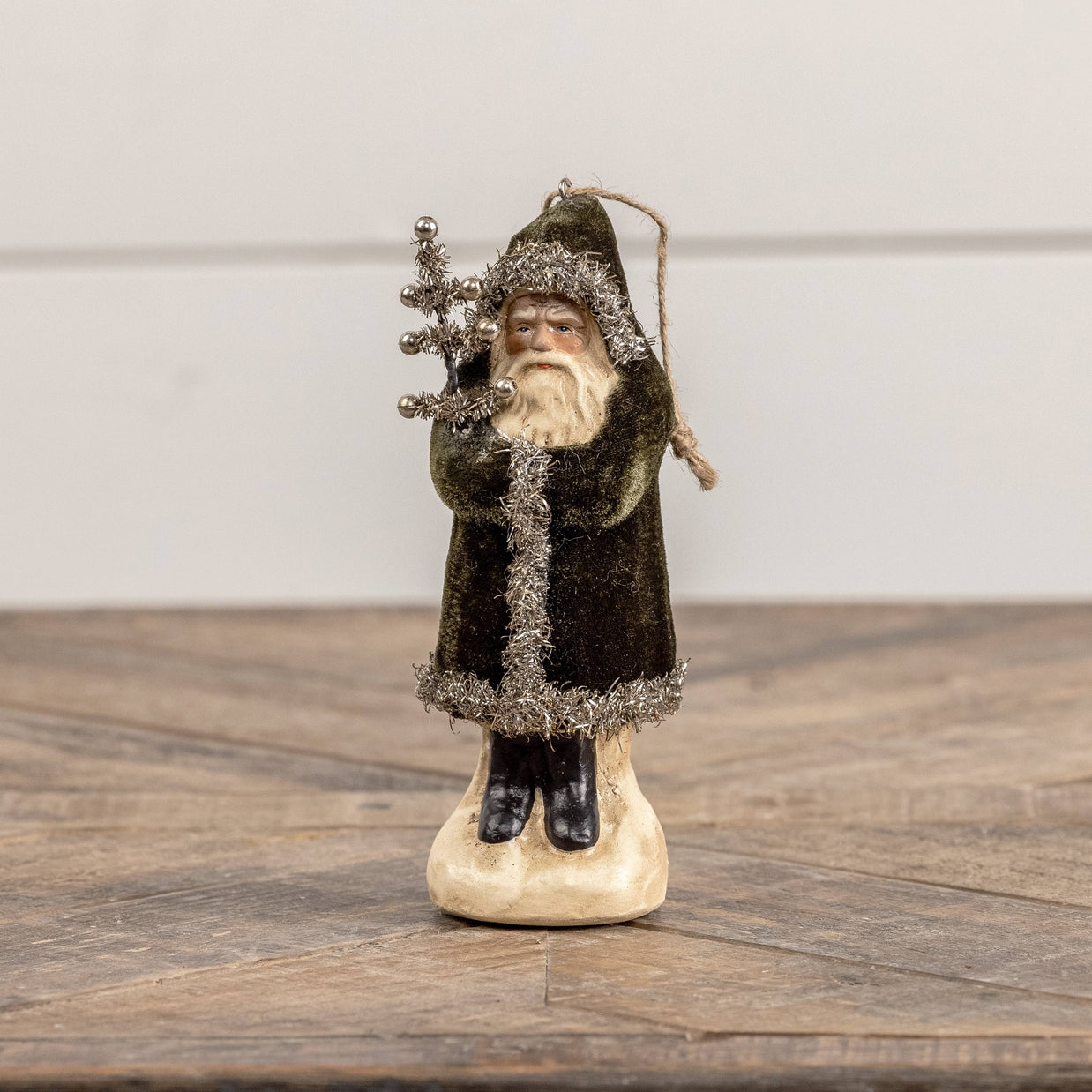 Decorative figure of a bearded man in a dark coat holding a staff on a wooden surface.