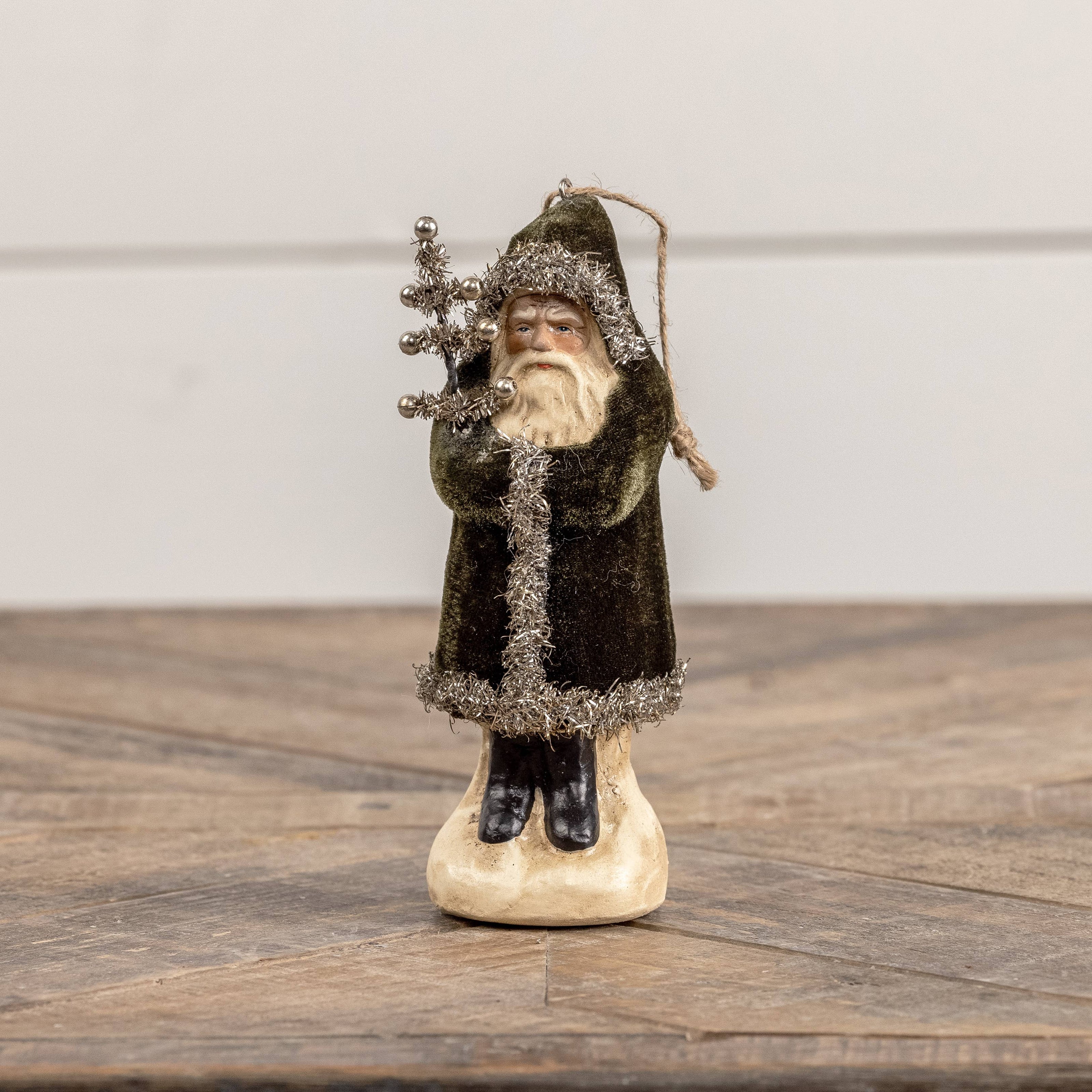 Decorative figure of a bearded man in a dark coat holding a staff on a wooden surface.
