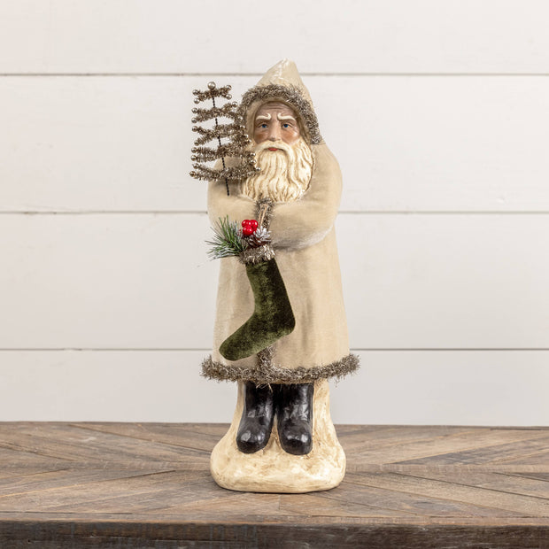 Decorative figure of a bearded man holding a tree and a stocking on a wooden surface with a white wooden panel background.