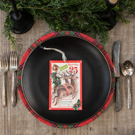 Christmas-themed place setting with a black plate, red plaid charger, and vintage card.