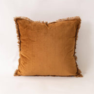 Brown velvet pillow with frayed edges on a white background