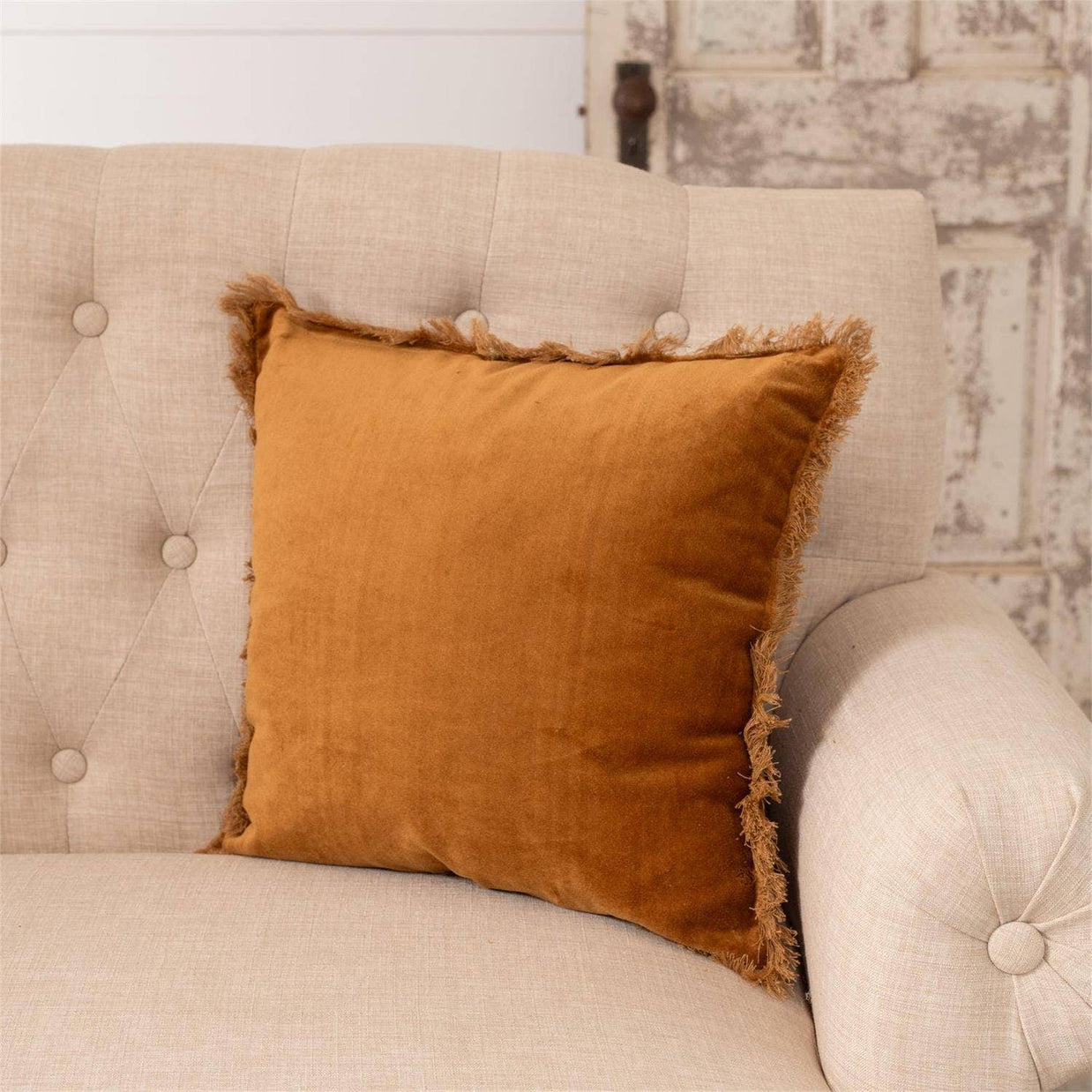 Brown pillow on a beige sofa with a rustic wall background