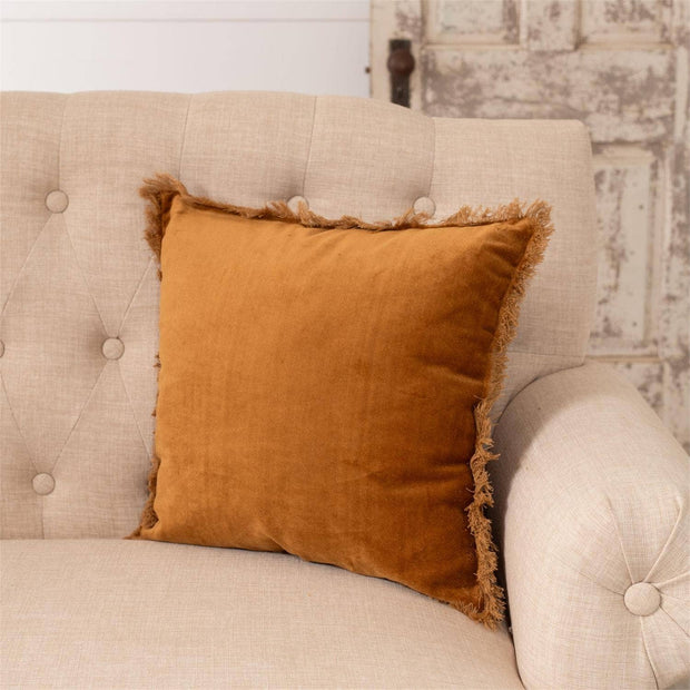 Brown pillow on a beige sofa with a rustic wall background