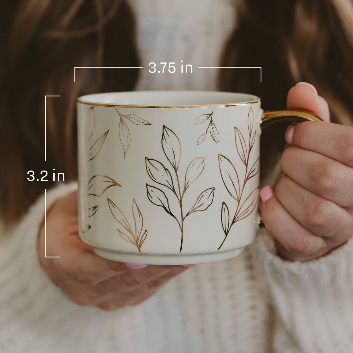 Person holding a decorative mug with leaf patterns and measurements