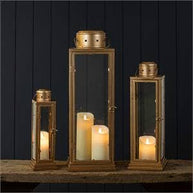 Set of three gold lanterns with candles inside on a dark background
