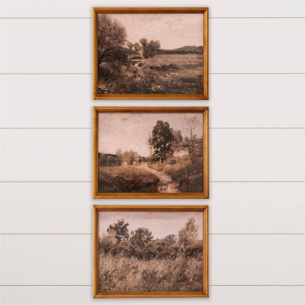 Three framed landscape prints on a white wooden wall