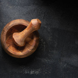 Wooden mortar and pestle on a dark stone surface