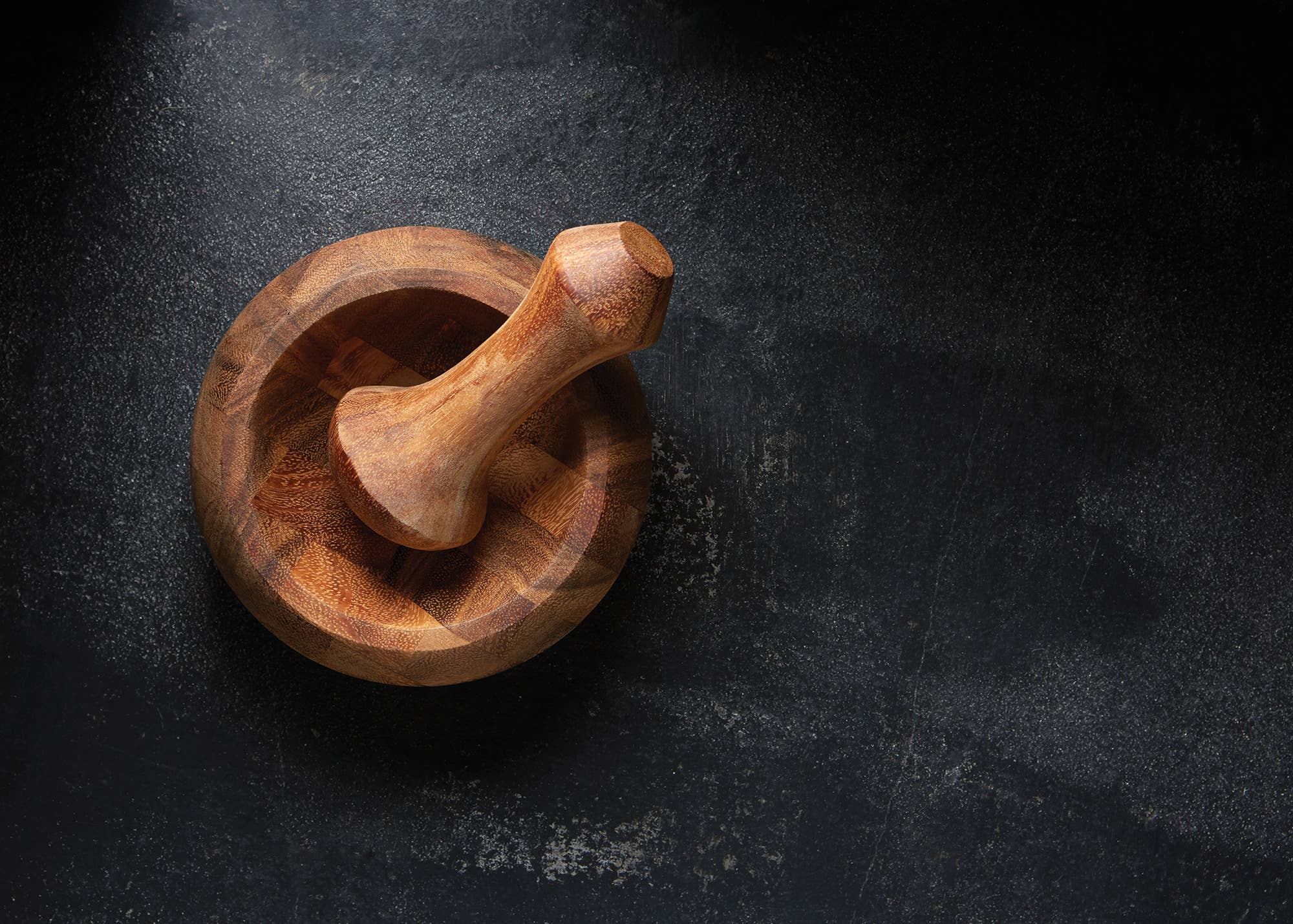 Wooden mortar and pestle on a dark stone surface