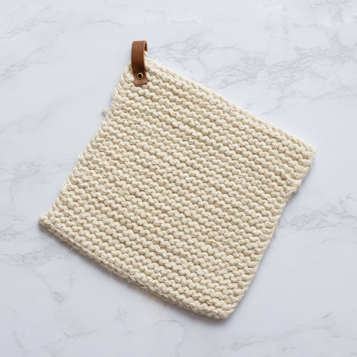 Beige woven potholder with leather strap on a light gray background