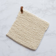 Beige woven potholder with leather strap on a light gray background
