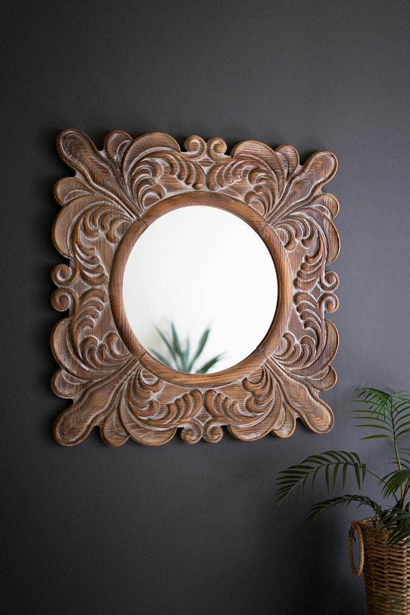 Decorative wooden mirror with intricate carvings on a dark wall.