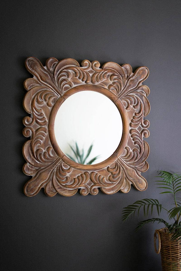Decorative wooden mirror with intricate carvings on a dark wall.