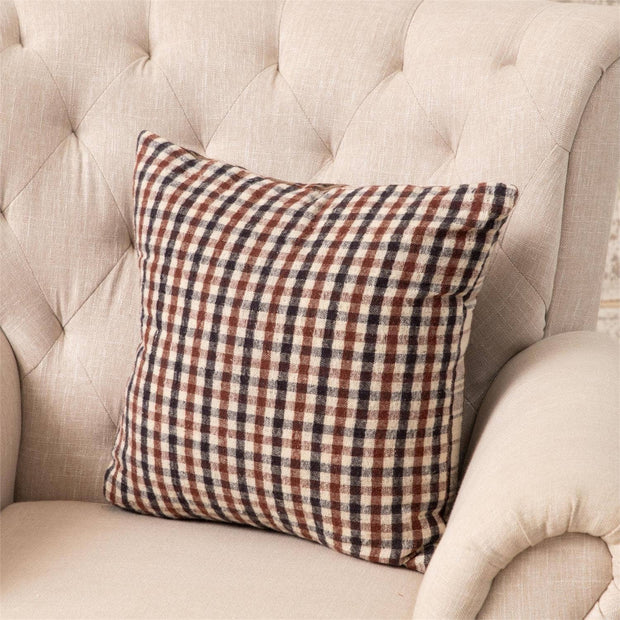 Plaid pillow on a beige tufted sofa