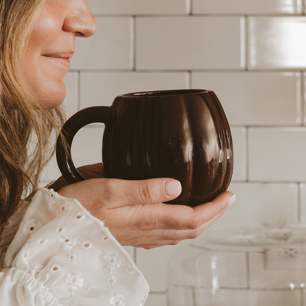 Person holding a brown mug in a kitchen setting