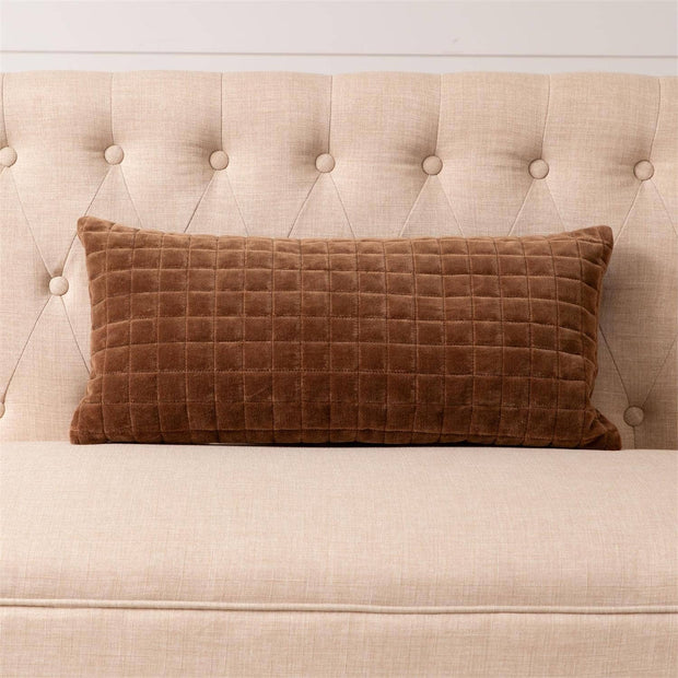 Brown checkered pillow on a beige tufted headboard