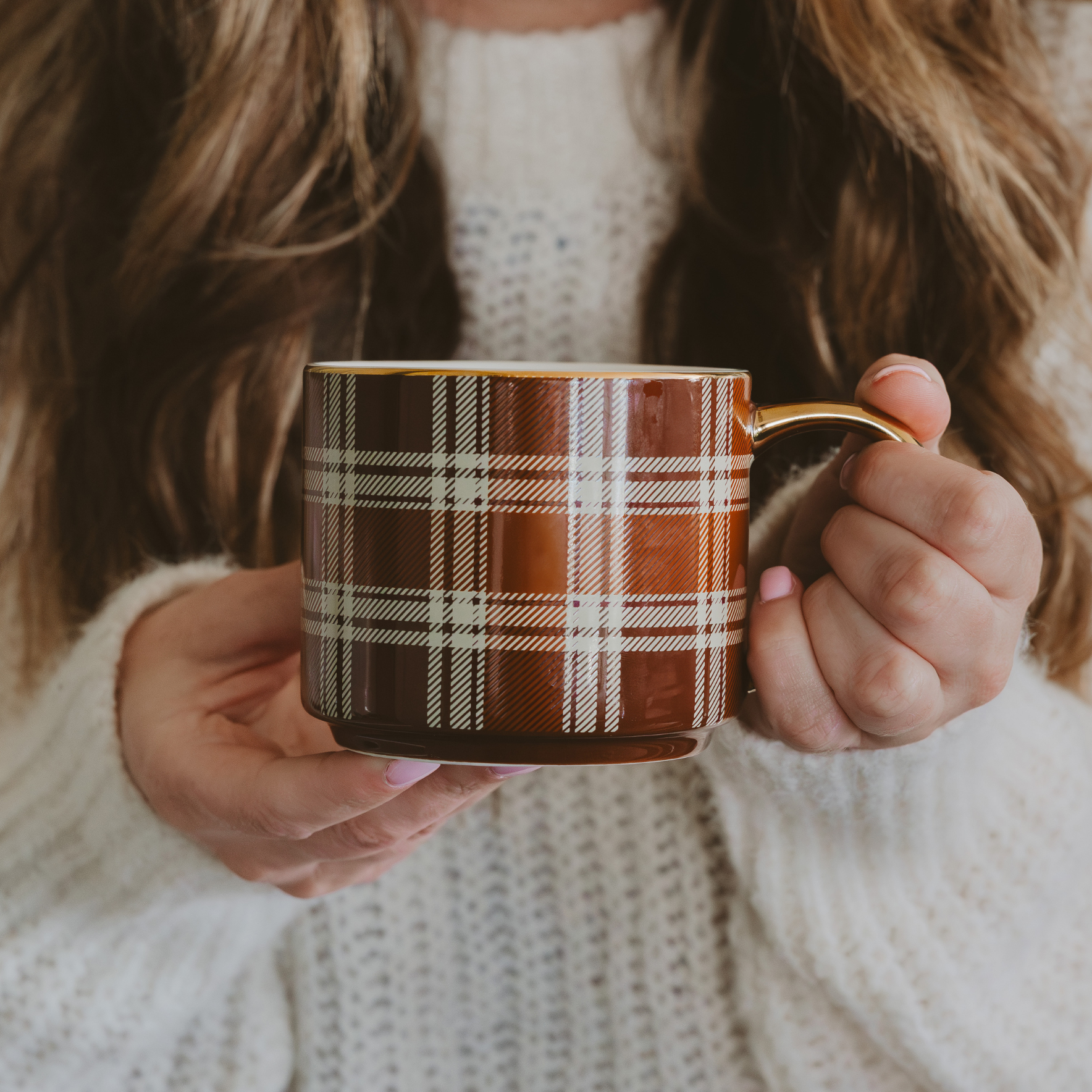Person holding a plaid mug with a soft focus background