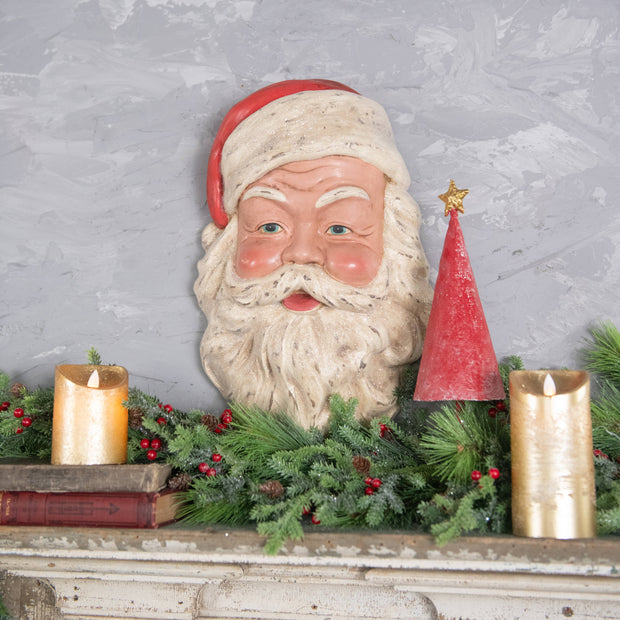 Decorative Santa Claus head with candles and greenery on a textured wall background