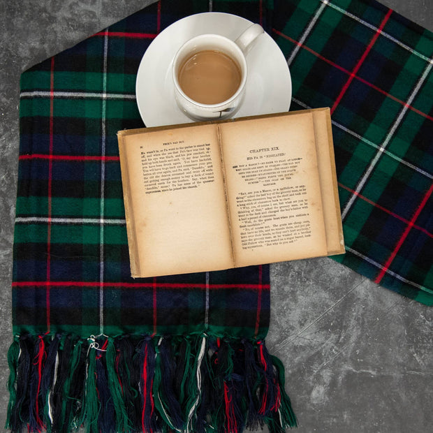 Open book on a plaid fabric with a cup of coffee