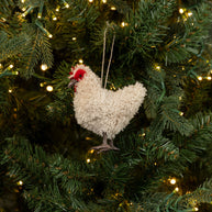 Decorative chicken ornament hanging on a Christmas tree with lights.