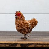 Small model of a rooster on a wooden surface with a white background