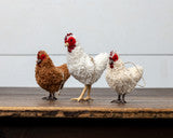 Three chickens standing on a wooden surface with a light gray background