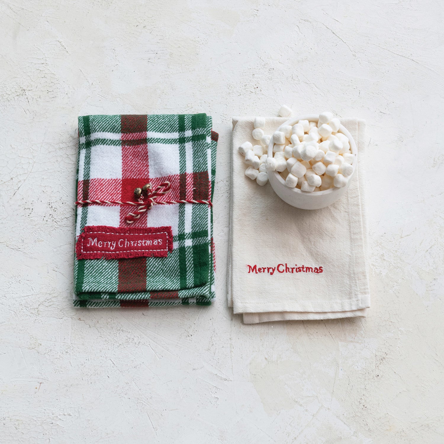 Two Christmas-themed napkins with 'Merry Christmas' text on a light surface.