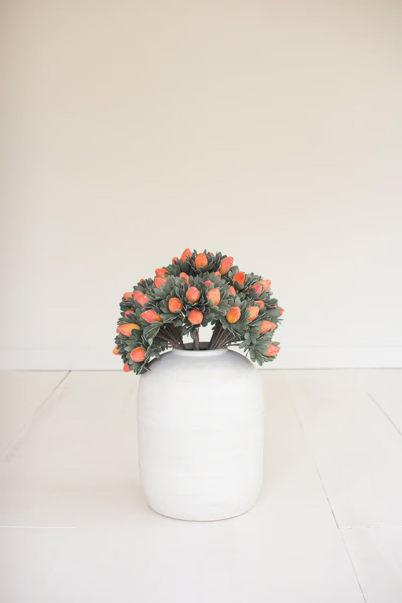Small wreath with orange flowers on a white vase against a plain background