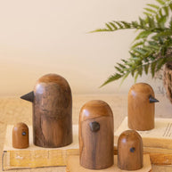 Wooden bird figurines on a wooden stand with a plant in the background