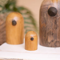 Three wooden ornaments on a white surface with a blurred natural background