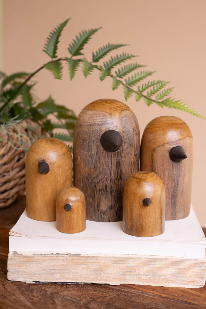 Set of wooden birdhouses on a white stand with a plant in the background