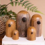 Set of wooden birdhouses on a white stand with a plant in the background