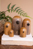 Set of wooden birdhouses on a white stand with a plant in the background