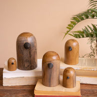 Set of wooden bird figurines on a wooden surface with a plant in the background