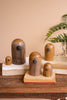 Set of wooden bird figurines on a wooden surface with a plant in the background